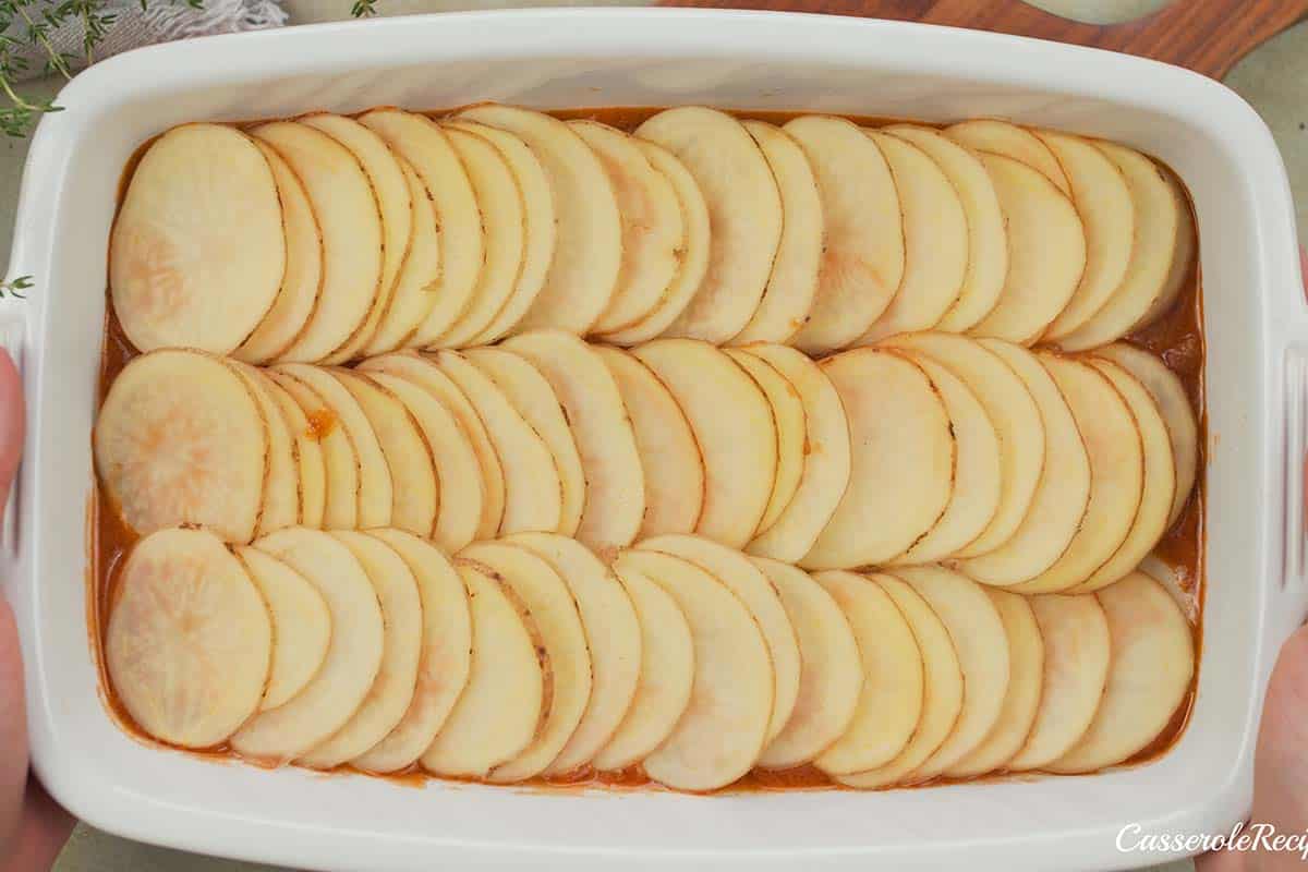 layering ingredients in a casserole dish to make beef hot pot casserole