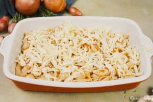 final step of making caramelized onion pasta bake by topping it with cheese prior to baking