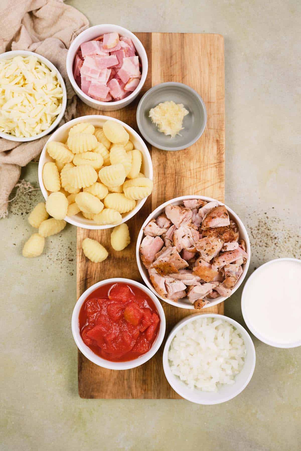 ingredients to make chicken and tomato gnocchi bake laid out on a table