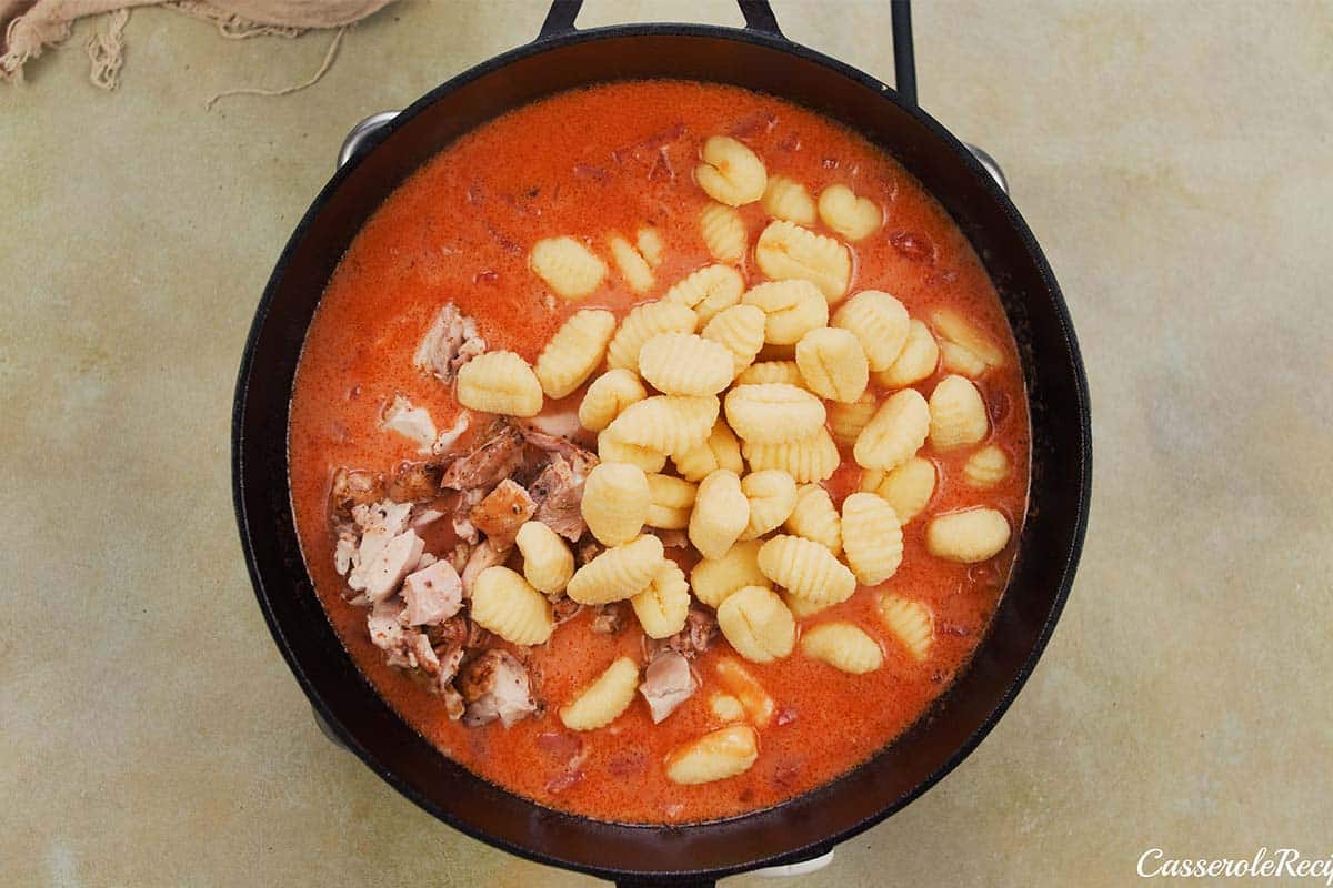 adding gnocchi to other ingredients to make chicken and tomato gnocchi bake