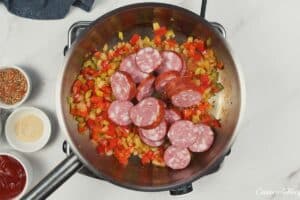 sausage being added to vegetables to make Louisiana Casserole