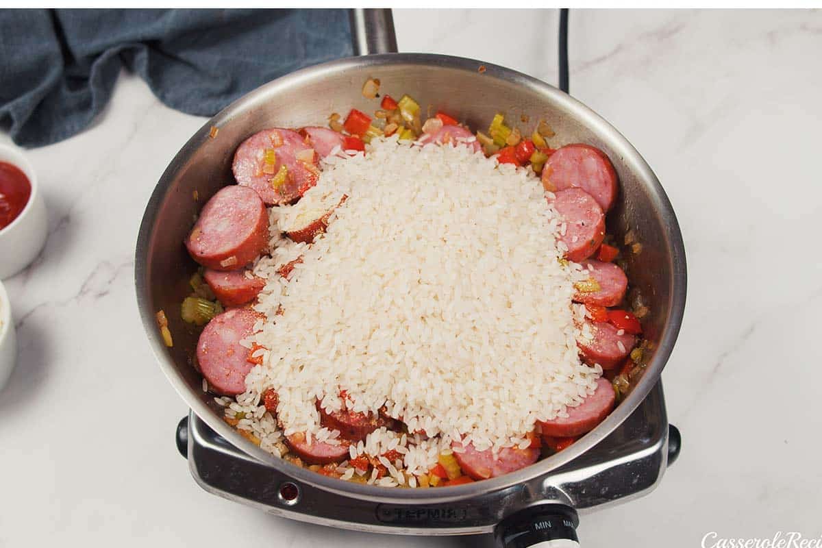 rice being added to a sauce pan to make Louisiana Casserole