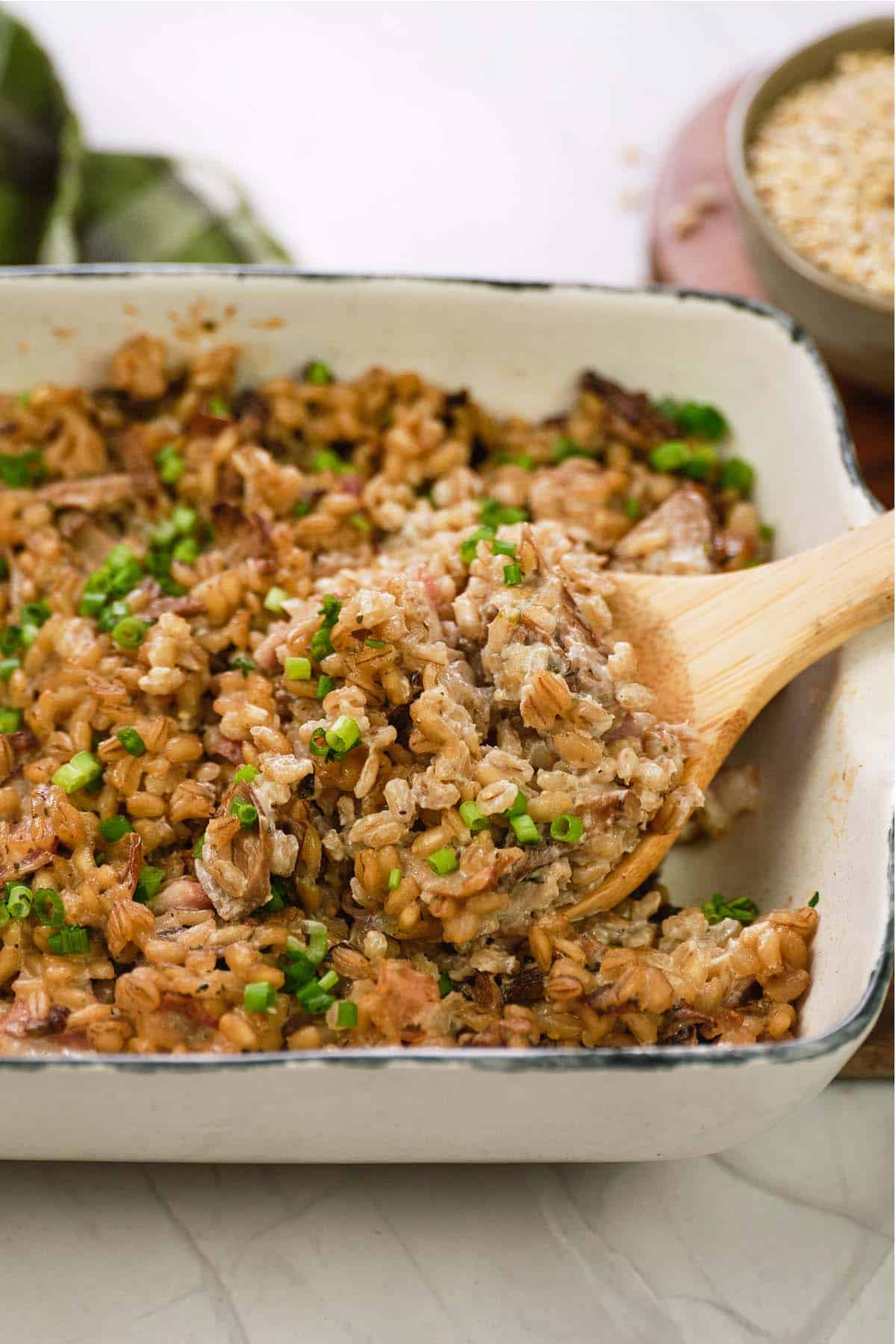 spoon scooping a serving of mushroom barley casserole from a baking dish