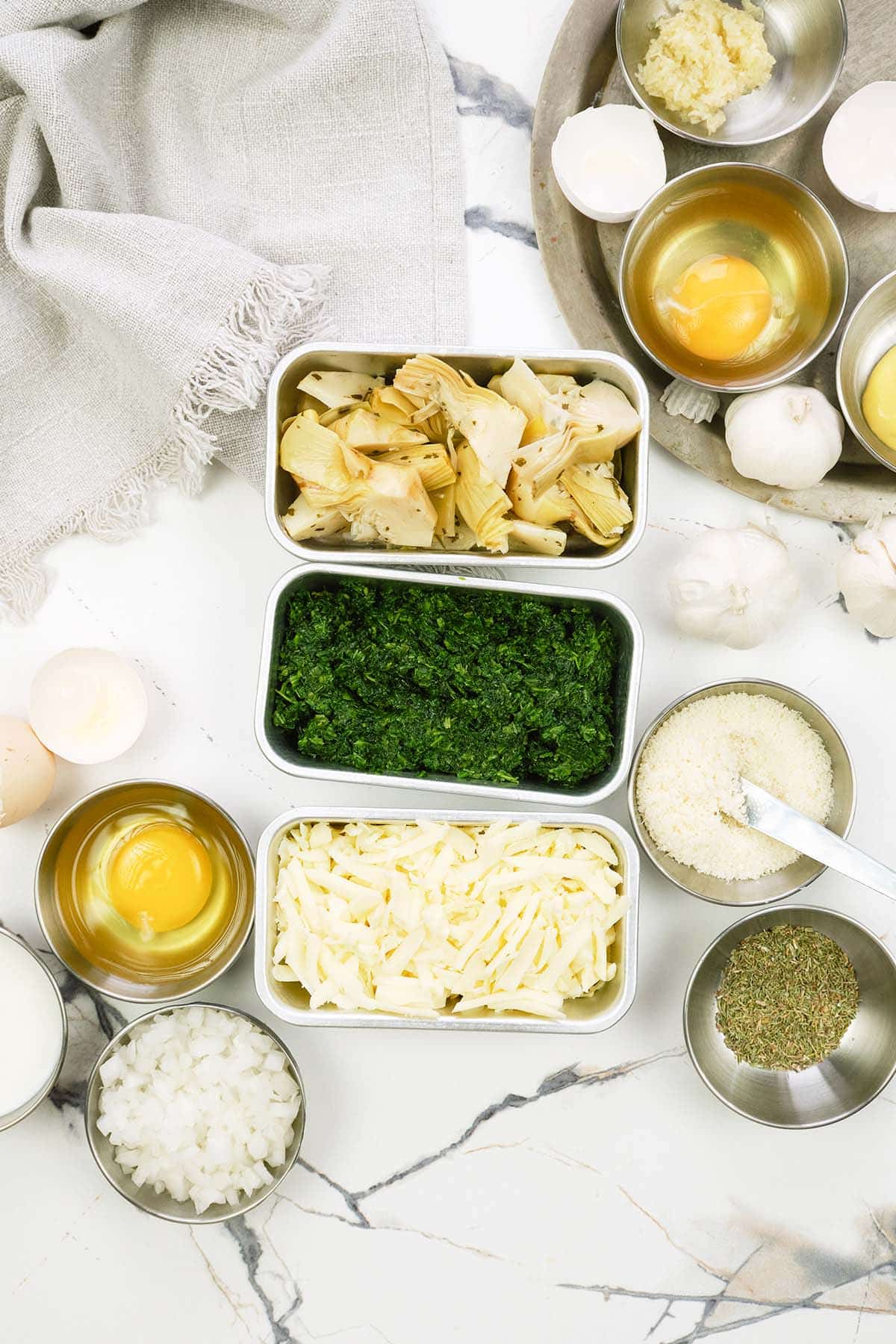 ingredients to make spinach artichoke breakfast casserole laid out on a table