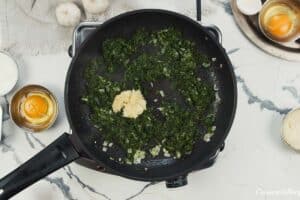 spinach and other ingredients being combined to make spinach artichoke breakfast casserole