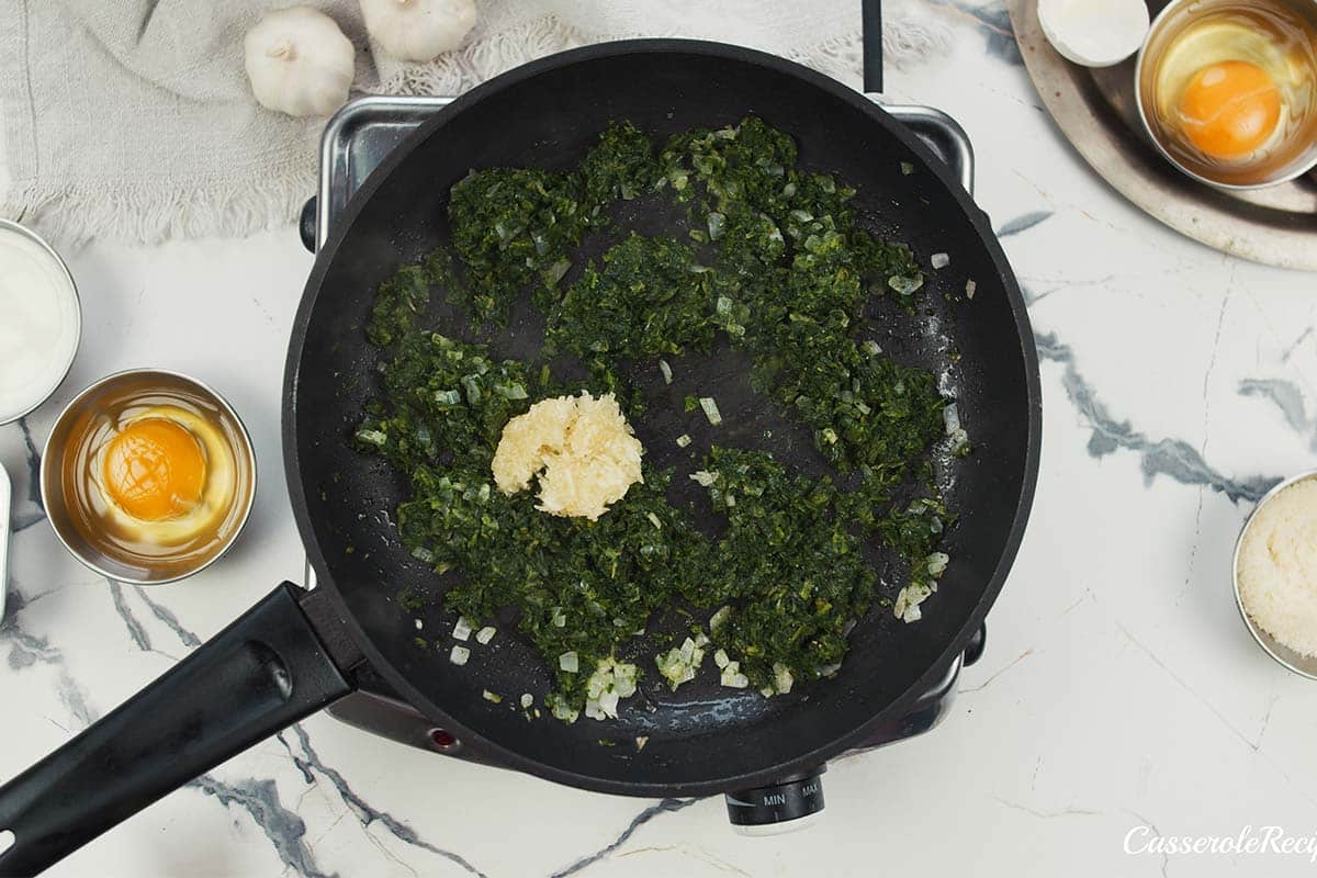 spinach and other ingredients being combined to make spinach artichoke breakfast casserole