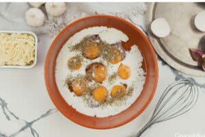 eggs and other ingredients in a bowl to make spinach artichoke breakfast casserole