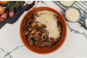 cooked mushrooms and other ingredients being combined in a bowl to make stuffed mushroom casserole