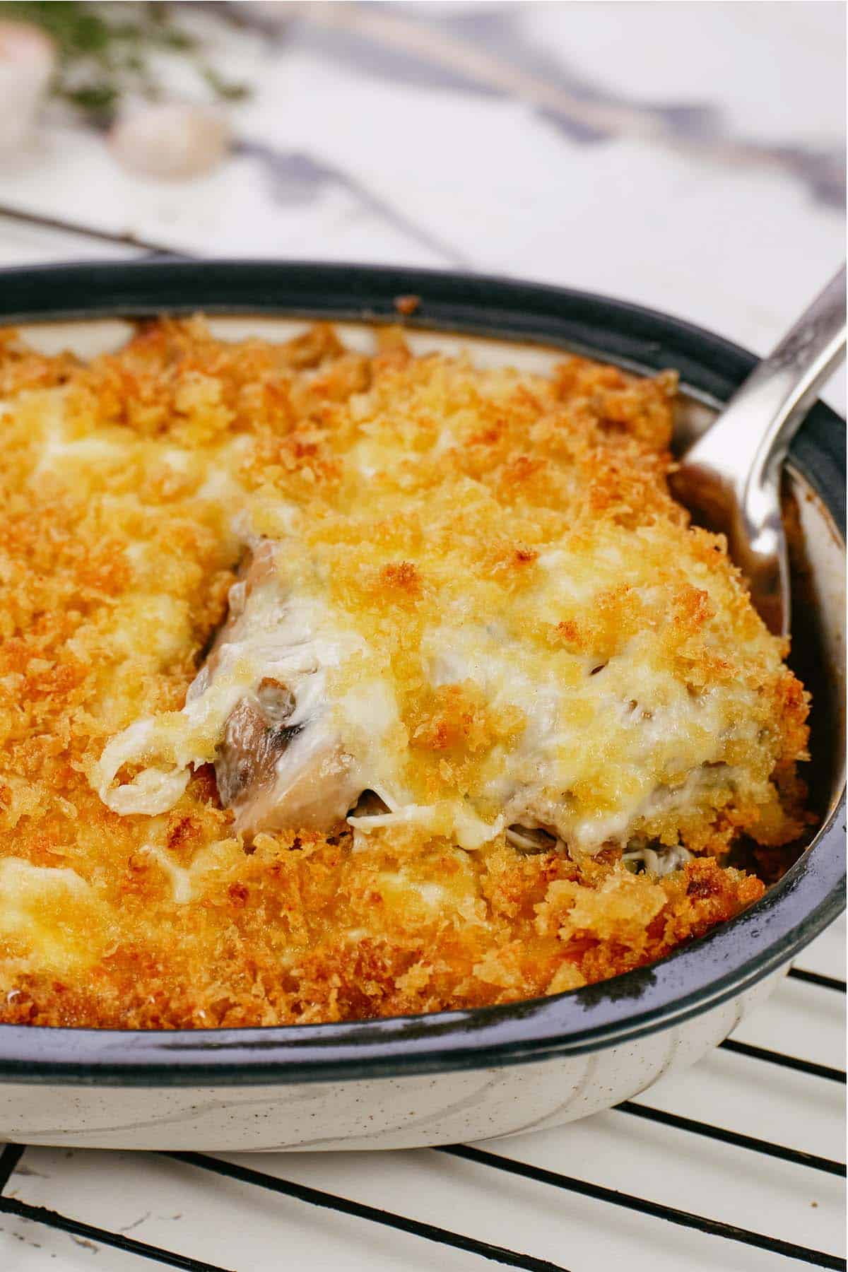 spoon lifting a serving of stuffed mushroom casserole from a baking dish