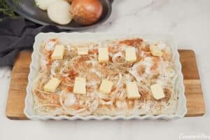 layering butter on top of the prepared onions and other ingredients to make Tennessee Onions