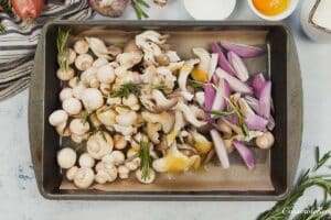 onion and mushrooms on a baking dish with oil on them being prepared to be baked to make yorkshire pudding traybake