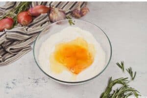adding eggs to other ingredients in a bowl to make yorkshire pudding traybake