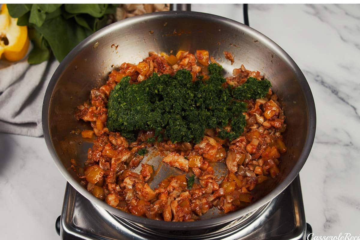 spinach being added to caramelized onion mixture to make Pizza Casserole with Couscous