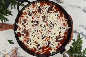 final step of topping Sloppy Joe Meatball Bake with cheese prior to baking