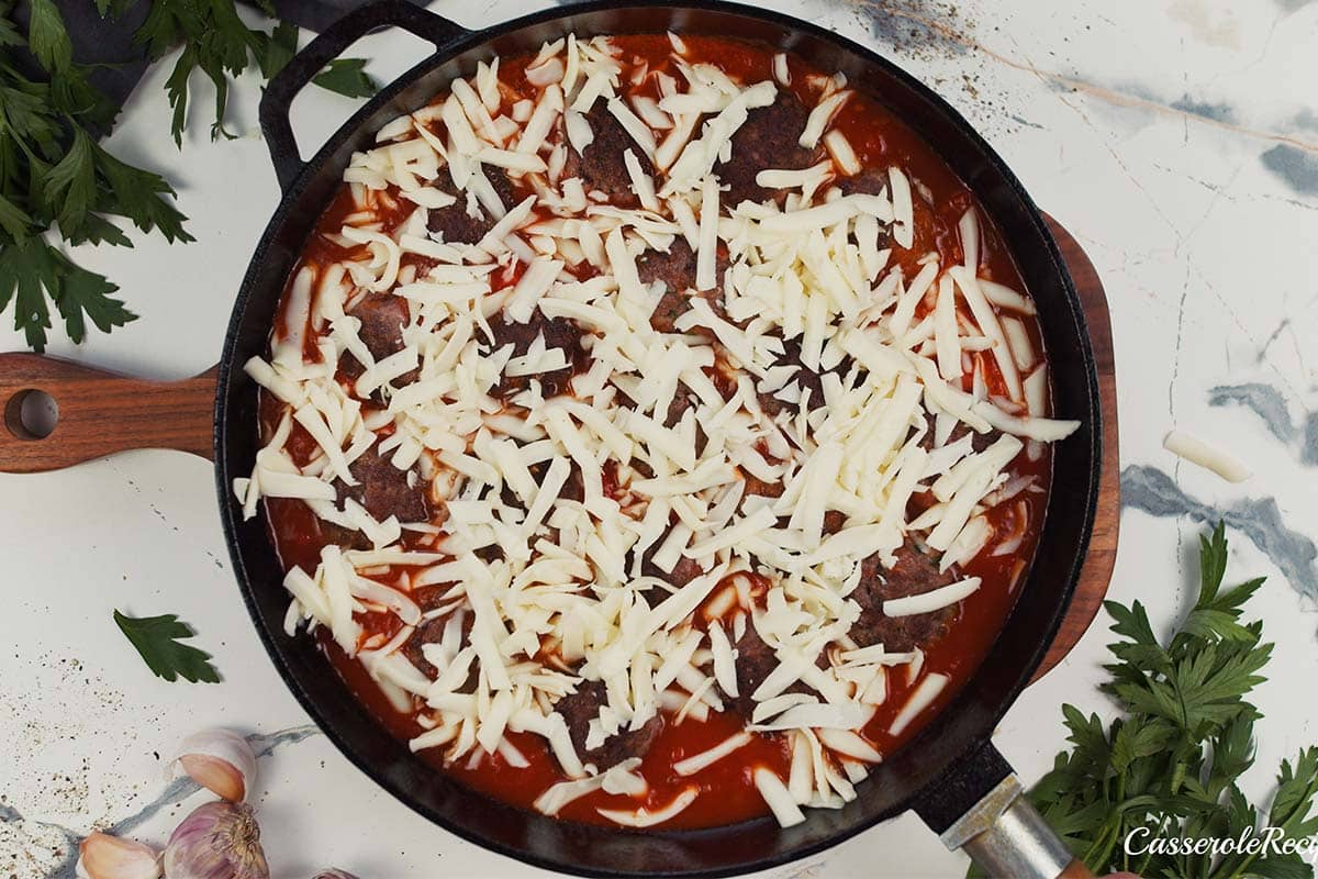 final step of topping Sloppy Joe Meatball Bake with cheese prior to baking