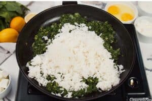 rice and spinach being combined in a cast iron dish to make Spinach, Feta & Rice Casserole