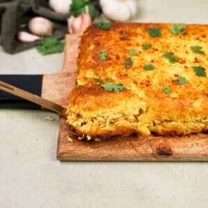 spatula lifting a serving of Tah-Cheen (persian baked chicken and rice) from a cutting board