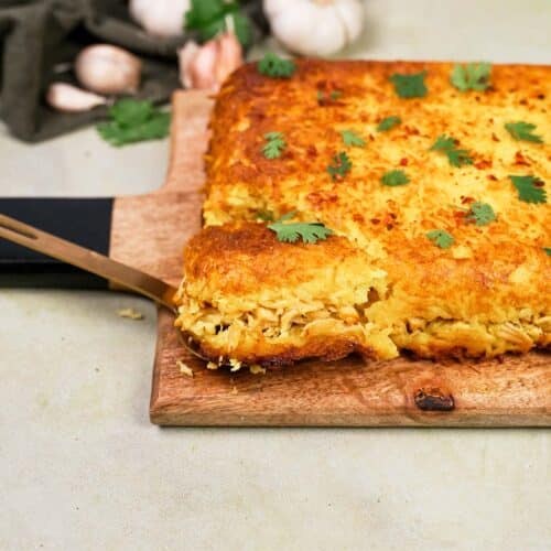 spatula lifting a serving of Tah-Cheen (persian baked chicken and rice) from a cutting board