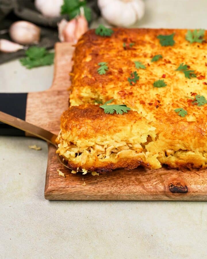 spatula lifting a serving of Tah-Cheen (persian baked chicken and rice) from a cutting board