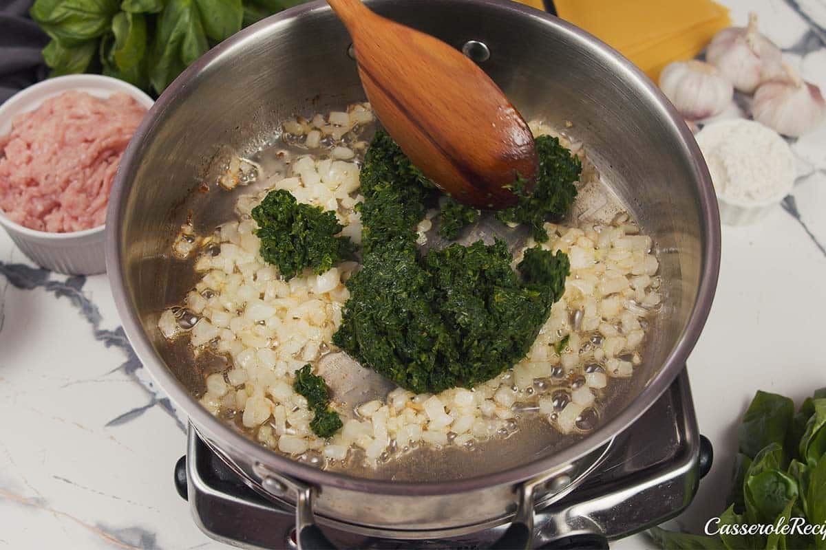 spinach being added to onions to sautee together to make baked skillet lasagna