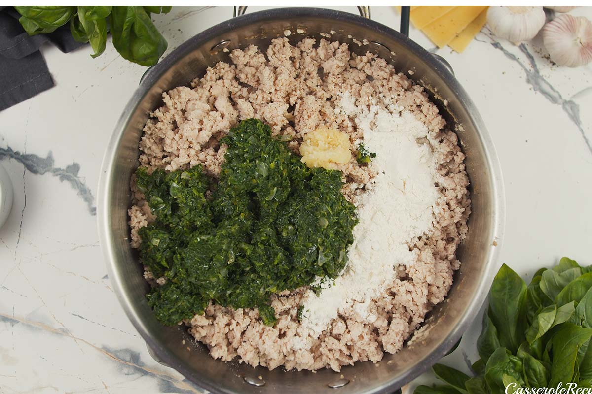 spinach and chicken being combined with other ingredients in a saute pan to make baked skillet lasagna