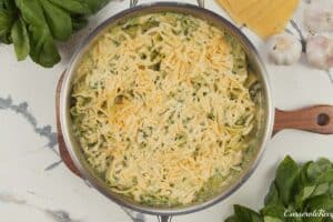 shredded cheese being added to the top of baked skillet lasagna prior to baking