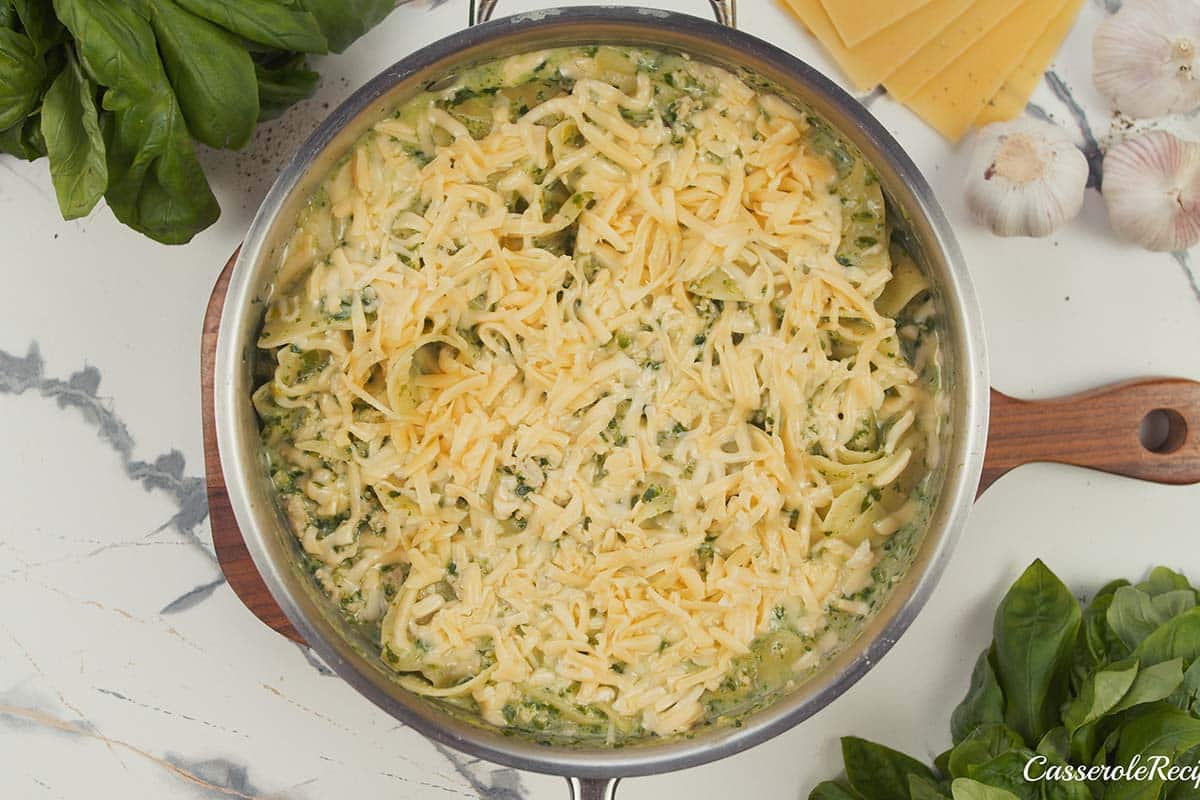 shredded cheese being added to the top of baked skillet lasagna prior to baking