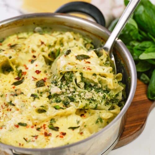 skillet of baked skillet lasagna being served with a large spoon