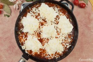 last step of making cheat lasagne bake by topping with cheese prior to baking