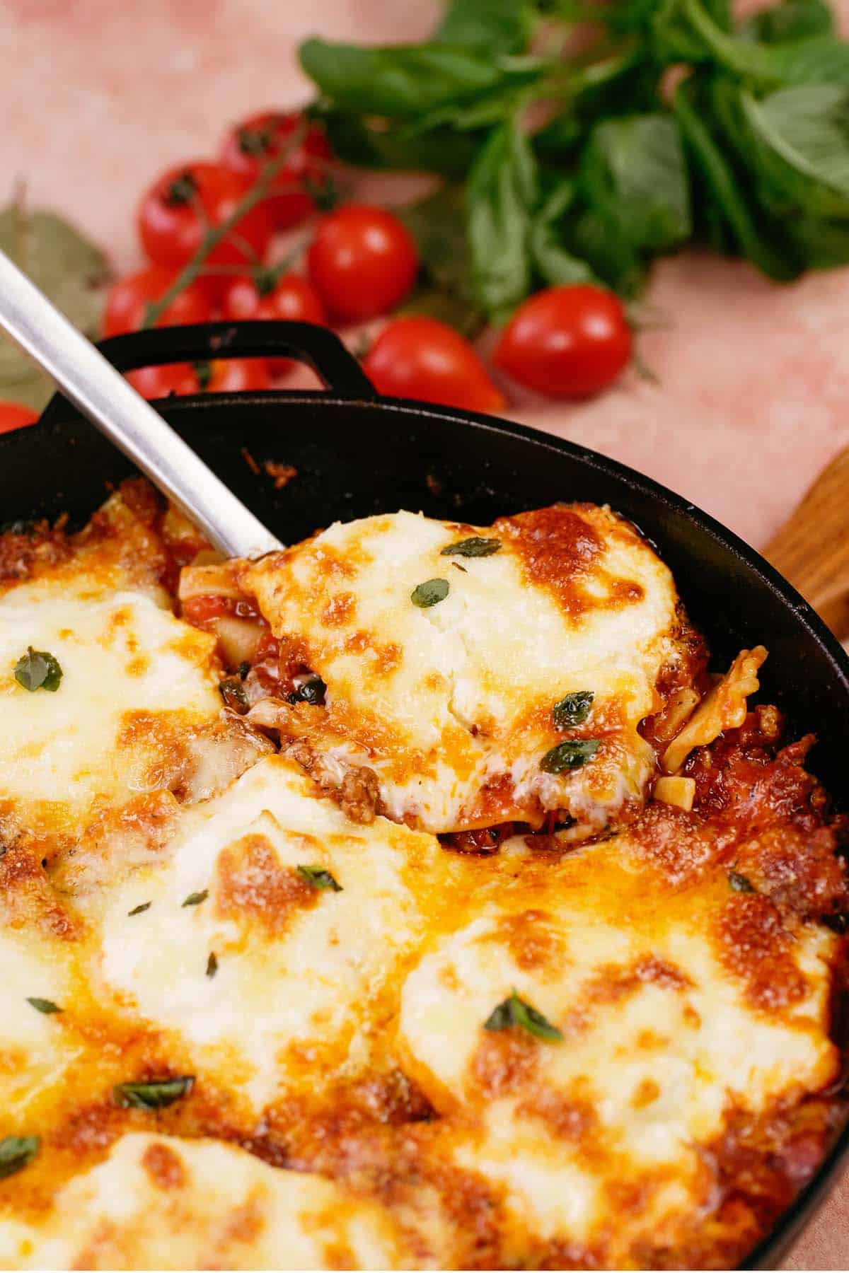 spoon lifting a serving of cheat lasagne bake from a cast iron skillet
