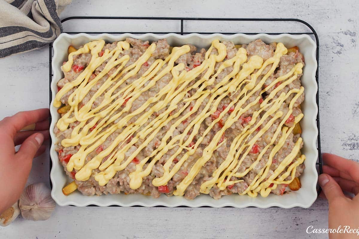 final step of drizzling cheese over the top of the filling prior to baking french fry casserole