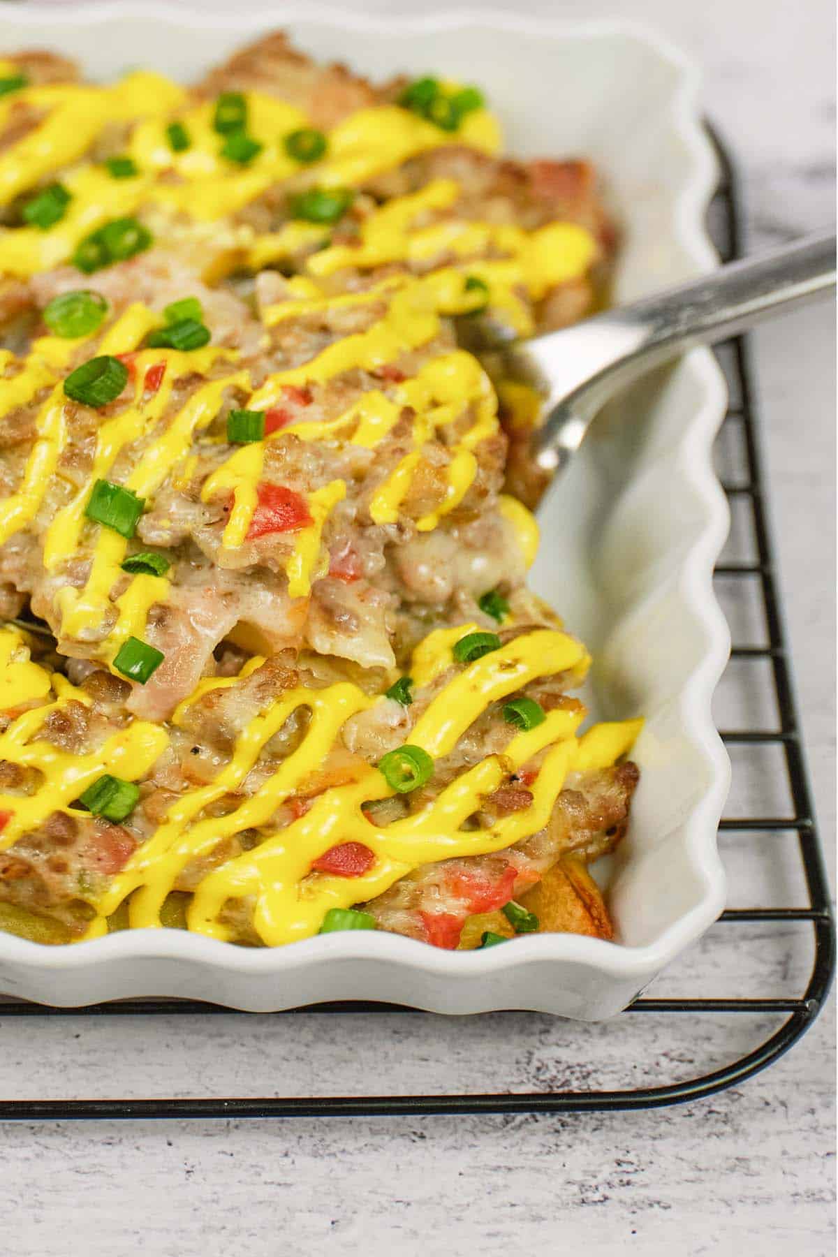 spoon lifting a serving of french fry casserole from a baking dish