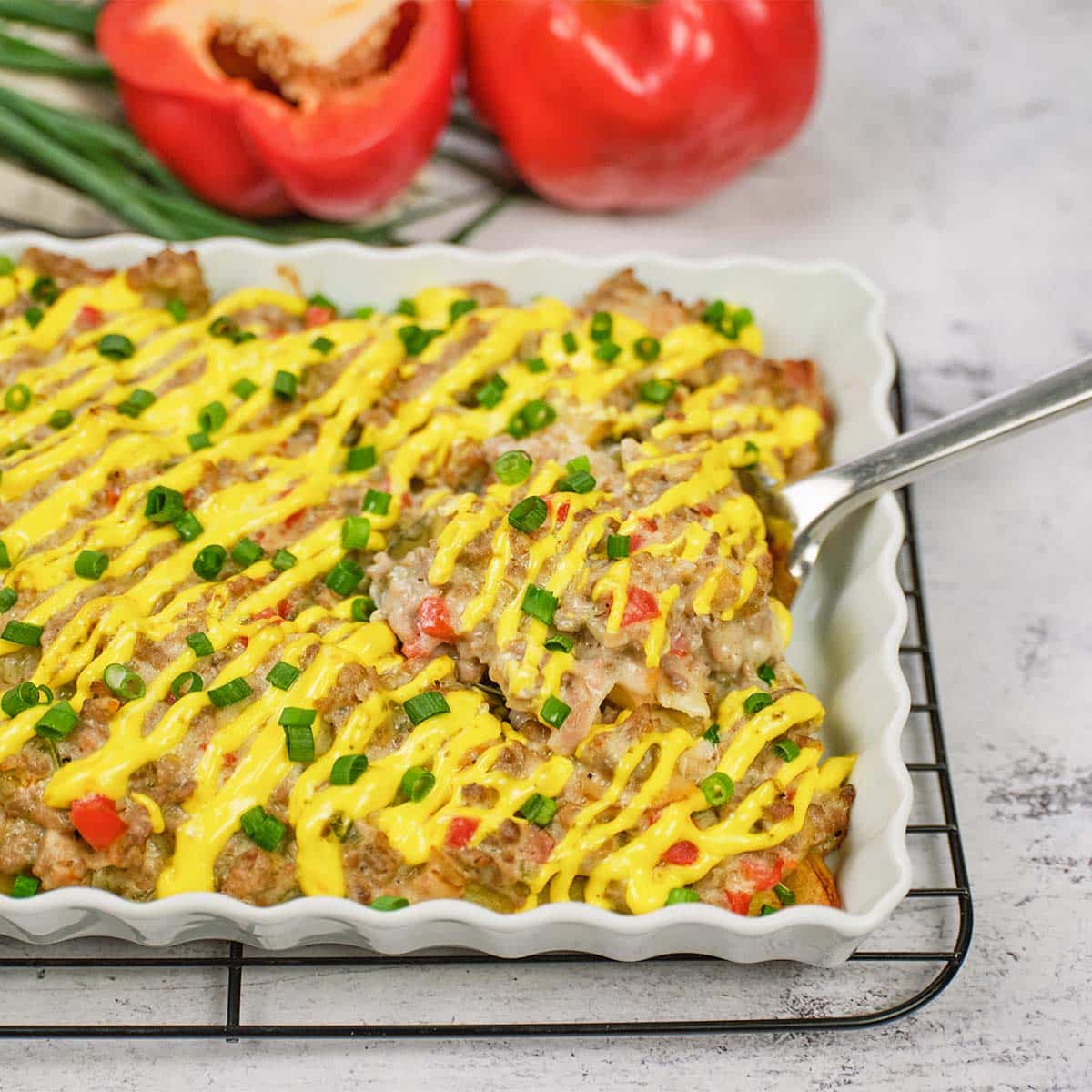 spoon scooping up a serving of french fry casserole from a baking dish