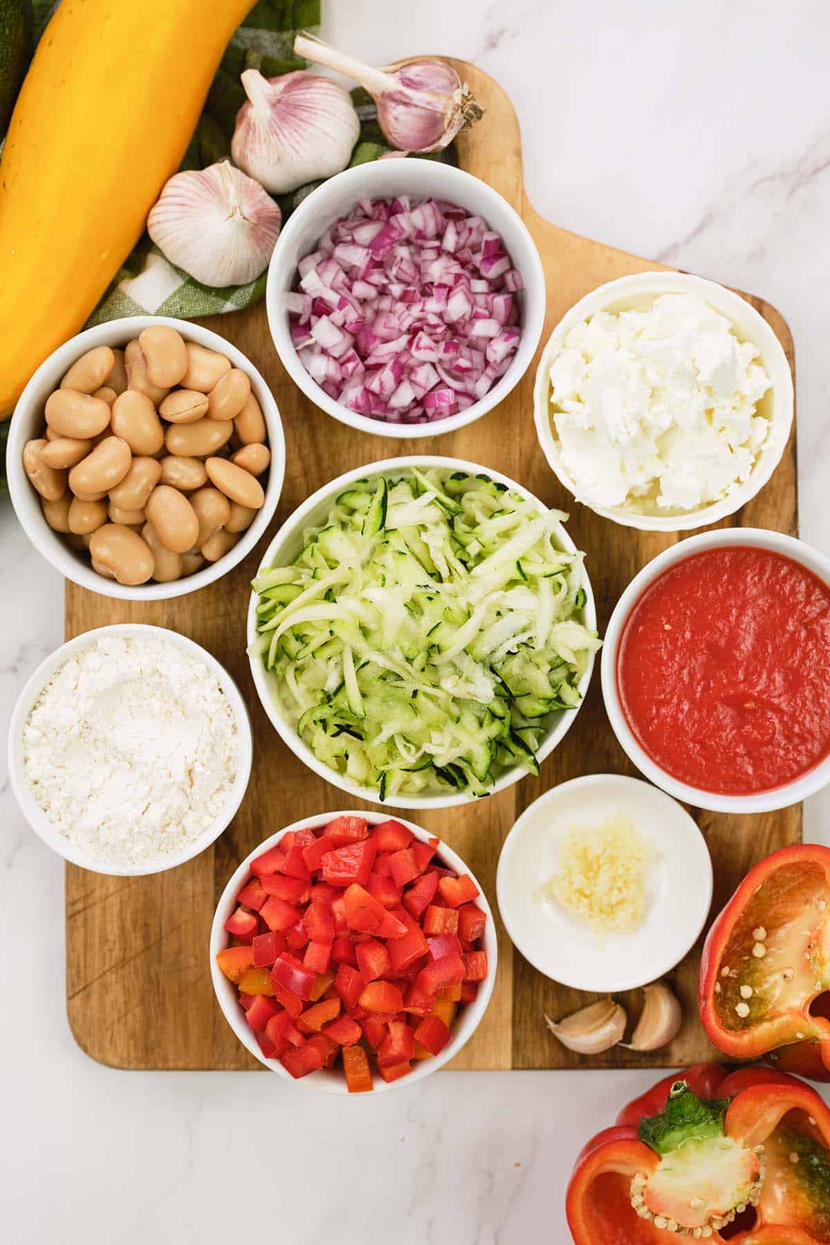 ingredients to make greek casserole with zucchini dumplings laid out on a table