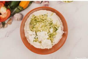 zucchini and other ingredients being combined to make greek casserole with zucchini dumplings