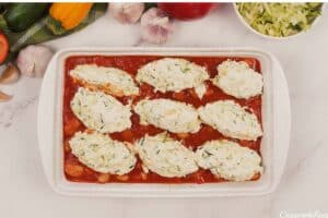 layering zucchini dumplings in a baking dish of sauce