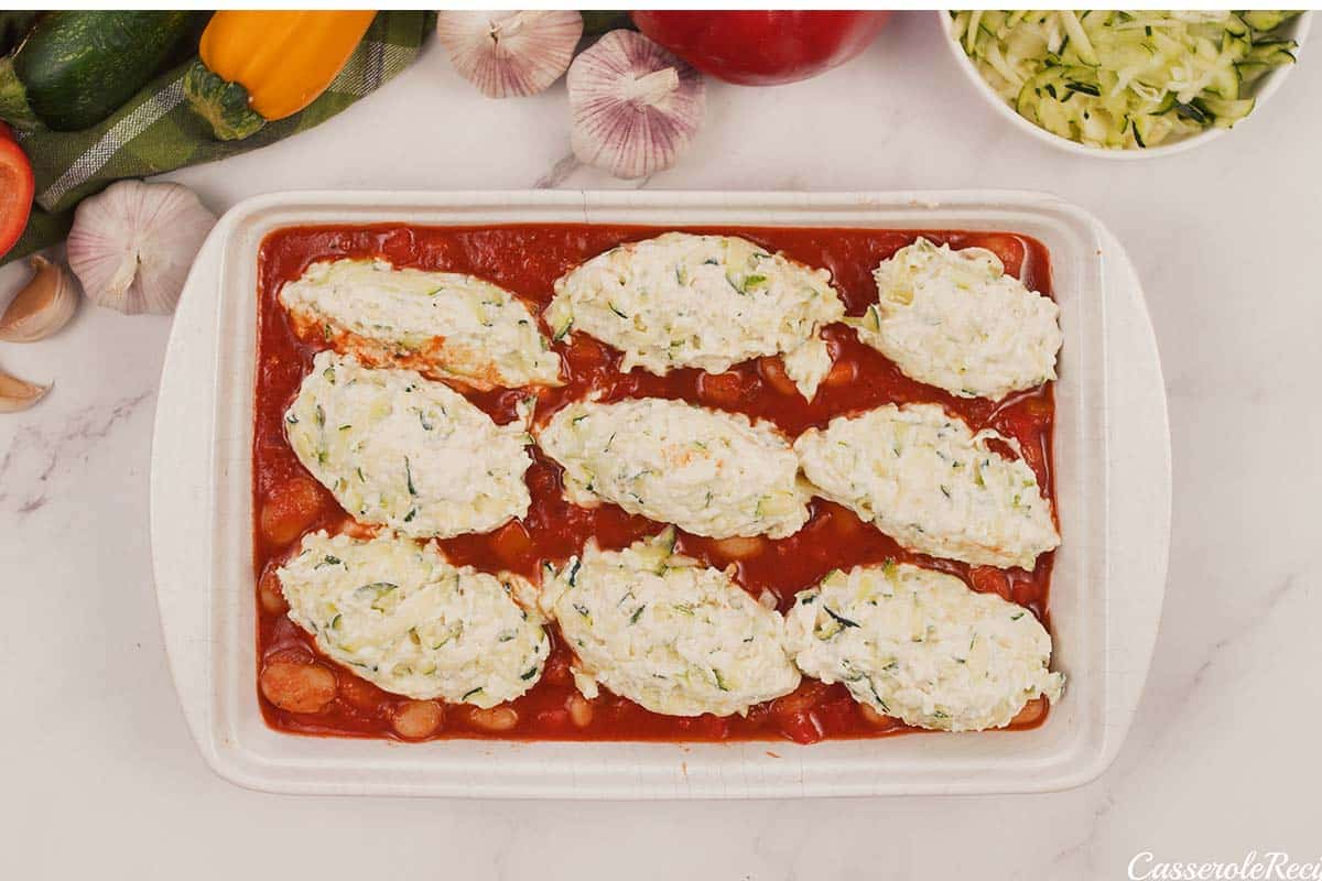 layering zucchini dumplings in a baking dish of sauce