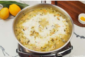 adding cream and stock to other ingredients to make greek rice and mussel casserole