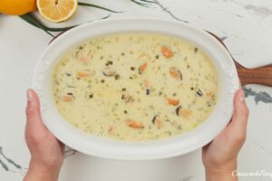 final step of putting filling in a baking dish to make greek rice and mussel casserole prior to baking