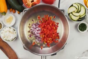 sauteeing onions and bell pepper to make greek vegetable casserole