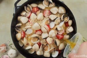 final step of adding broth to other ingredients to make italian baked rice and clams