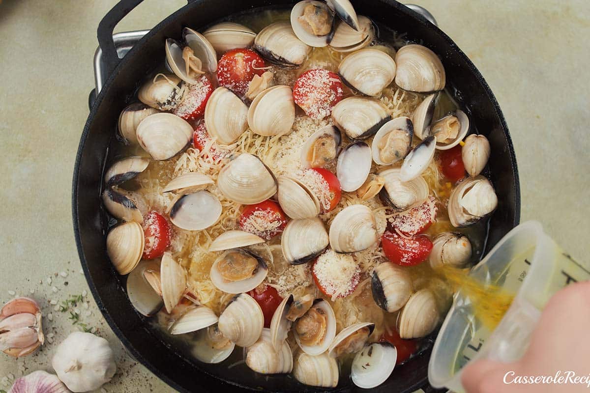 final step of adding broth to other ingredients to make italian baked rice and clams