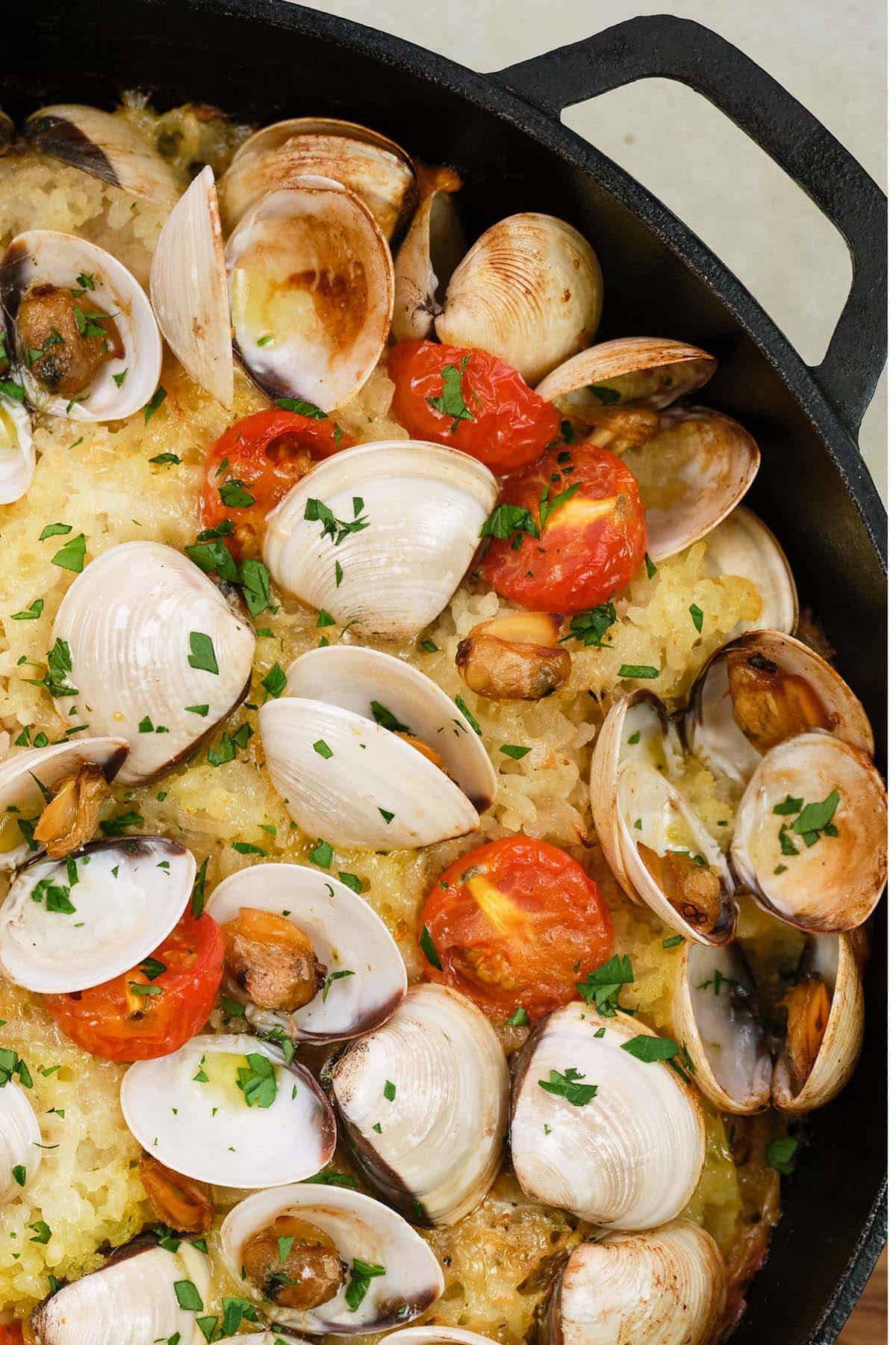 closeup of a cast iron skillet of italian baked rice and clams ready to be served