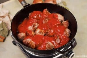 adding tomato sauce to the cooked meat and other ingredients to make kebab casserole