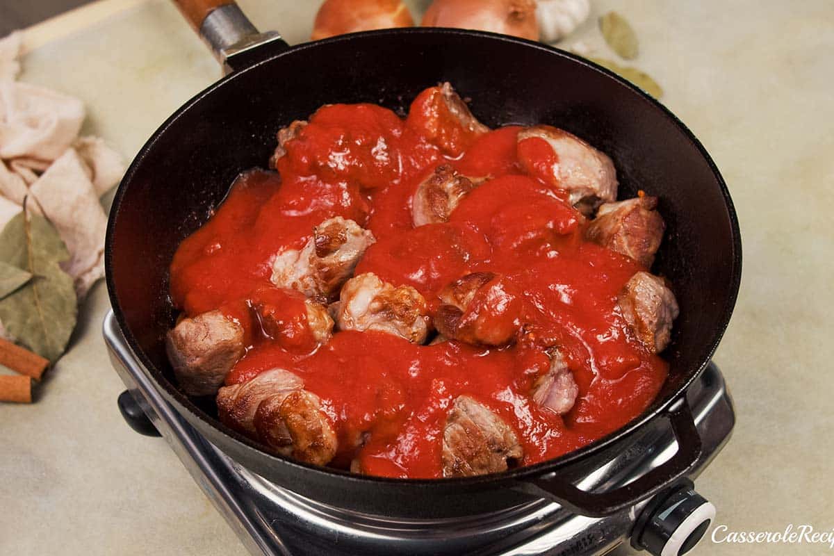 adding tomato sauce to the cooked meat and other ingredients to make kebab casserole