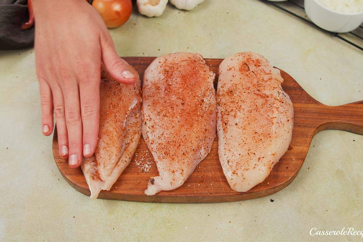 chicken being seasoned to make no-peek chicken casserole