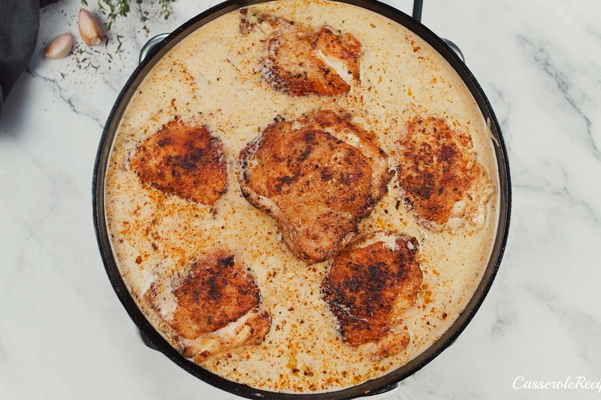 final step of arranging the chicken in the pan with the sauce to make One Pot Caribbean Jerk Chicken & Rice before baking