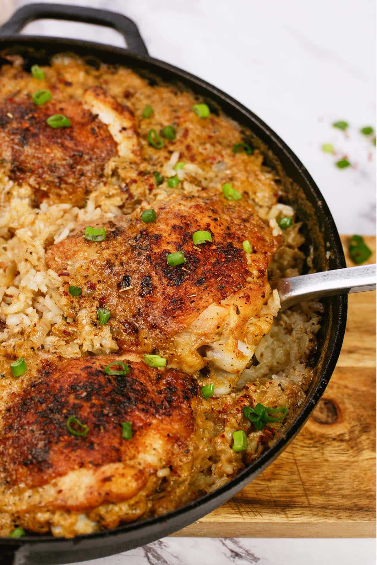 spoon scooping up a serving of One Pot Caribbean Jerk Chicken & Rice from a cast iron skillet
