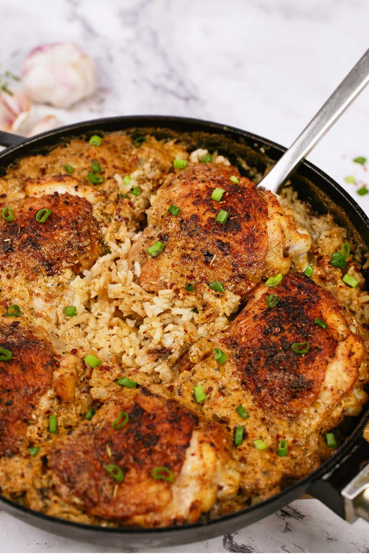 spoon scooping up a serving of One Pot Caribbean Jerk Chicken & Rice from a cast iron skillet