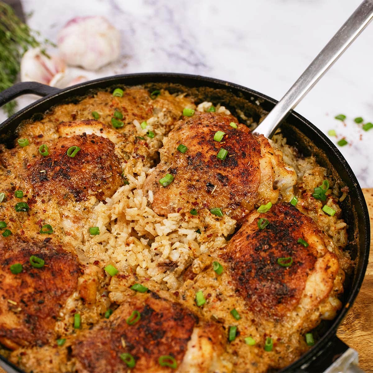 spoon lifting a serving of One Pot Caribbean Jerk Chicken & Rice from a cast iron dish